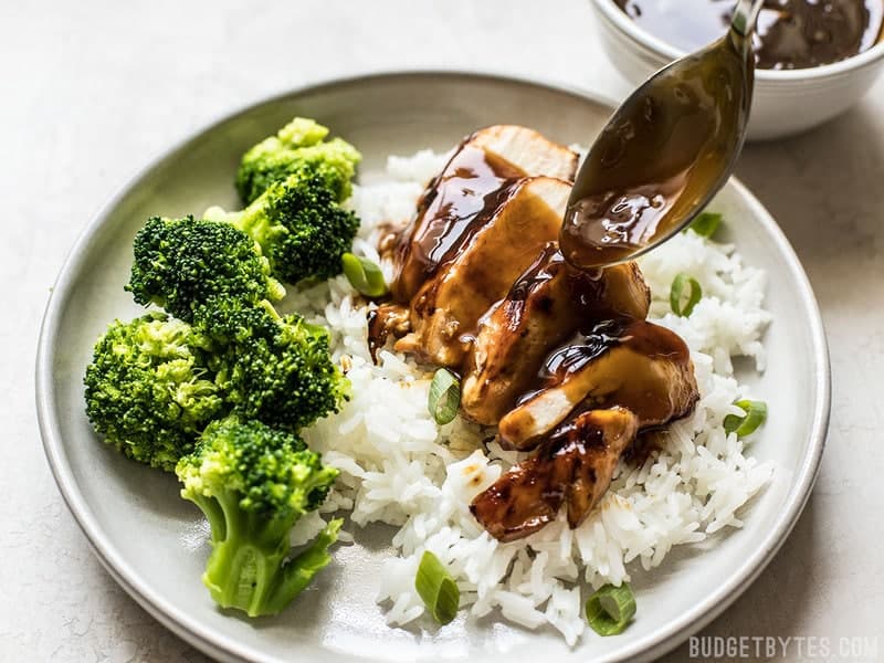 This Easy Homemade Teriyaki Sauce (or marinade) takes only a few minutes and five simple ingredients that can be kept on hand at all times. Perfect for last minute weeknight dinners! Budgetbytes.com Teriyaki Sauce being drizzled over sliced grilled chicken breast on a bed of rice