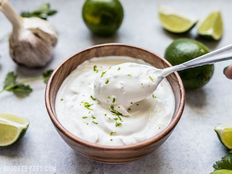A spoon scooping Lime Crema out of a small bowl