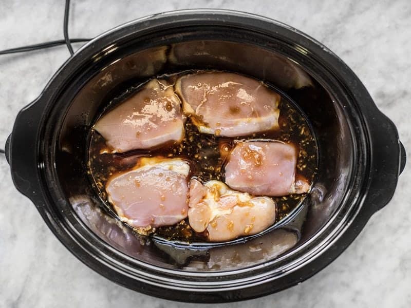 Pour pineapple teriyaki marinade over chicken thighs in slow cooker