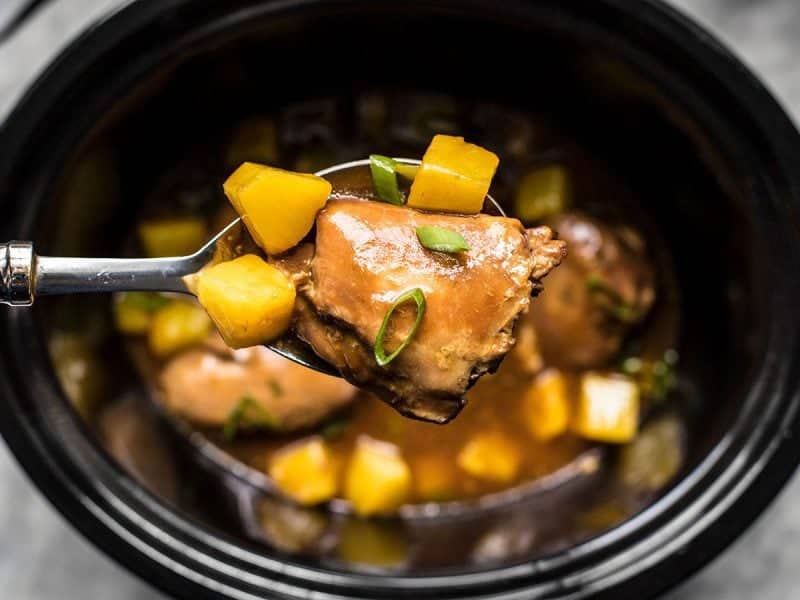 Close up of a large spoonful of Slow Cooker Pineapple Teriyaki Chicken being pulled from the slow cooker.