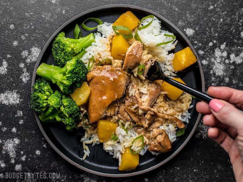A forkful of Slow Cooker Pineapple Teriyaki Chicken being lifted from the plate. 