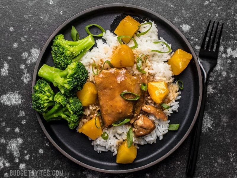 Slow Cooker Pineapple Teriyaki Chicken on a black stoneware plate with rice and broccoli