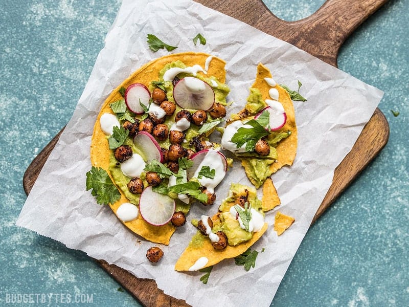 A Spiced Chickpea Tostada on a piece of parchment, broken into pieces