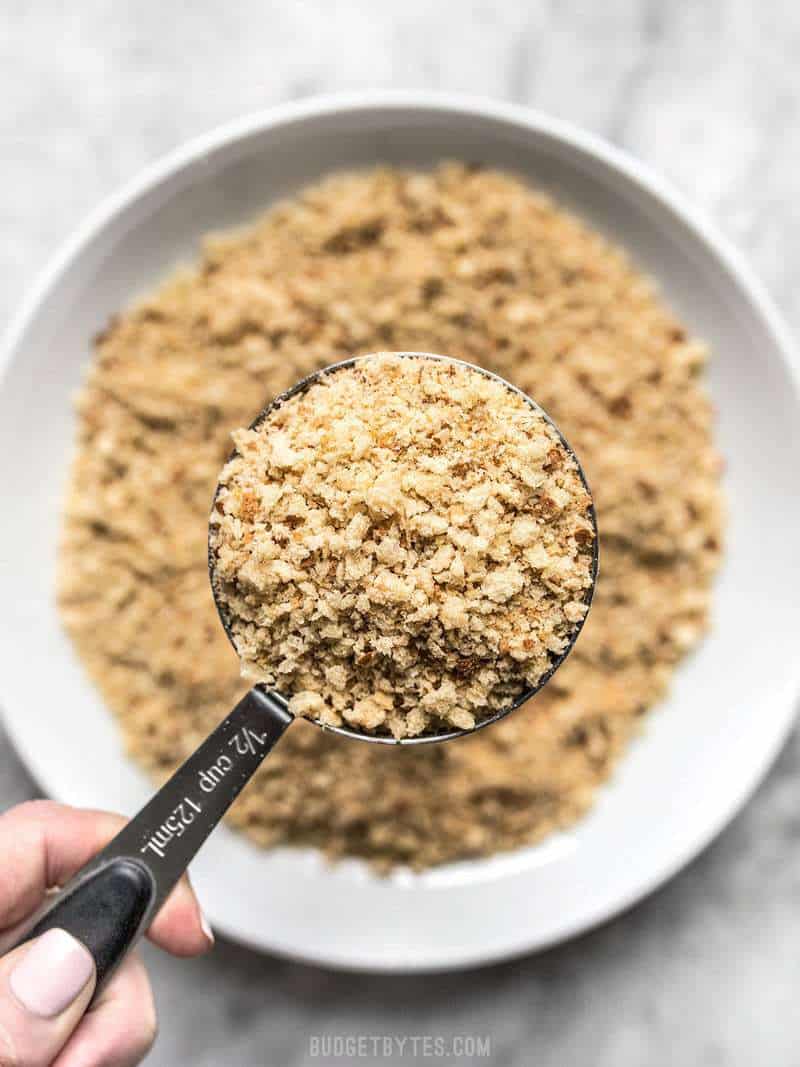 A measuring cup full of homemade breadcrumbs with the full bowl in the background