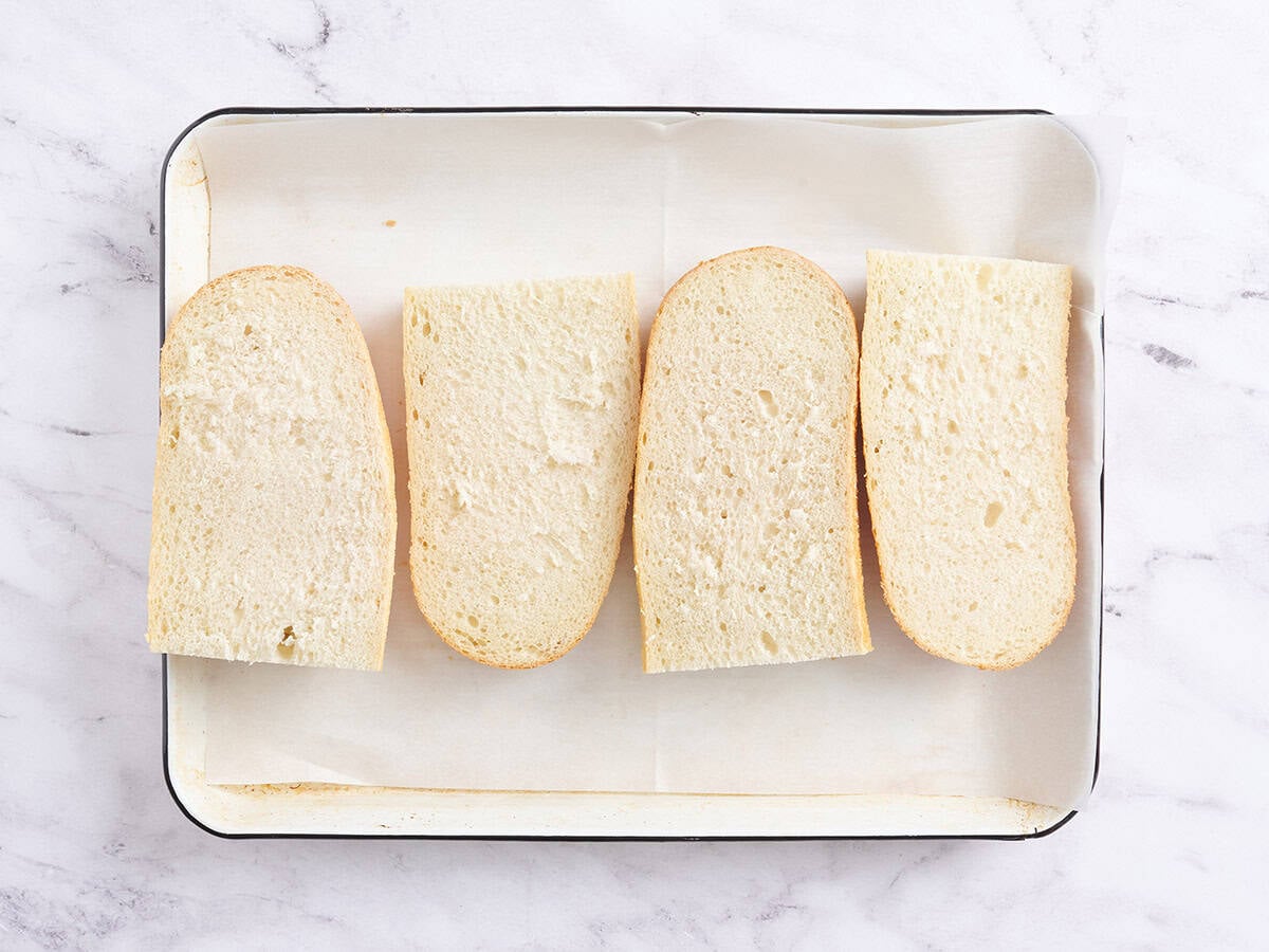 French bread quarters on a baking sheet.