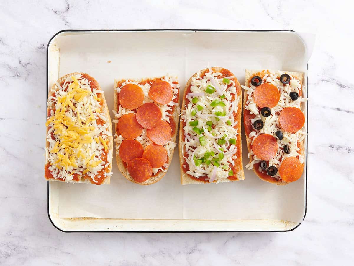 Toppings added to homemade French bread pizzas.