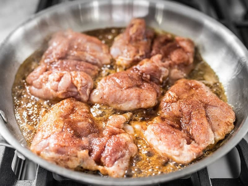 Chicken Thighs cooking in a hot skillet