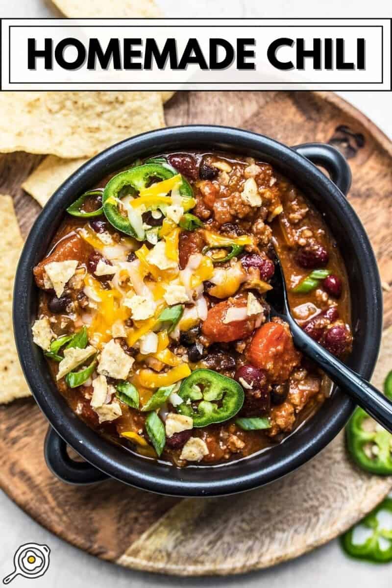 Overhead view of a bowl full of chili with toppings and a spoon.