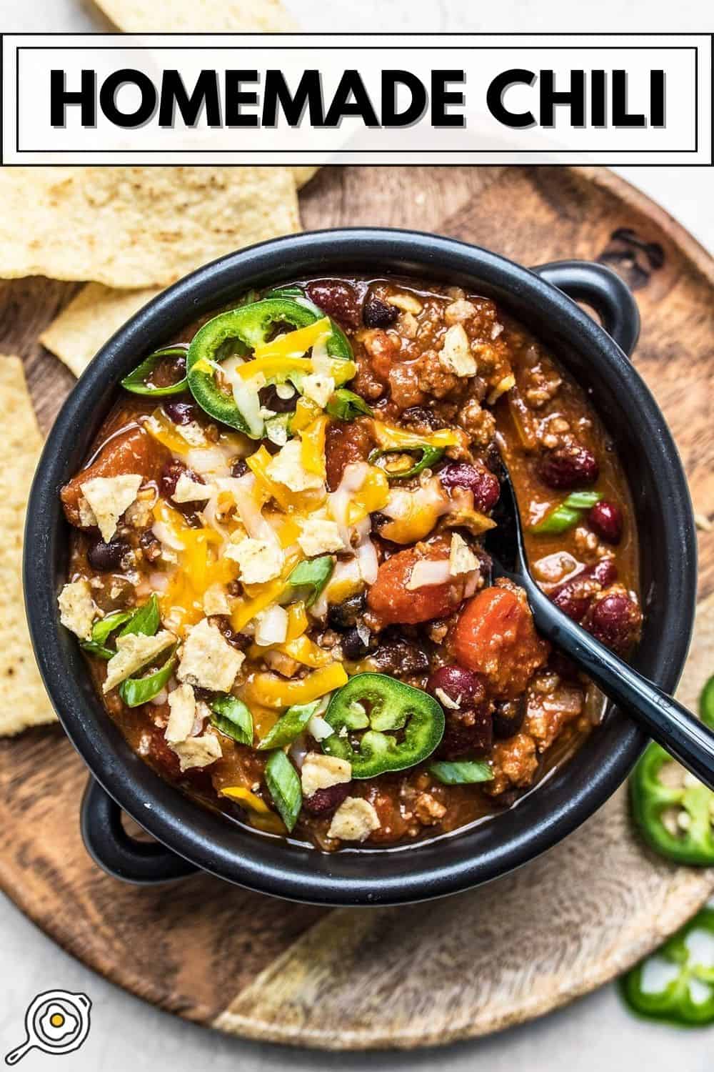 Overhead view of a bowl full of chili with toppings and a spoon.