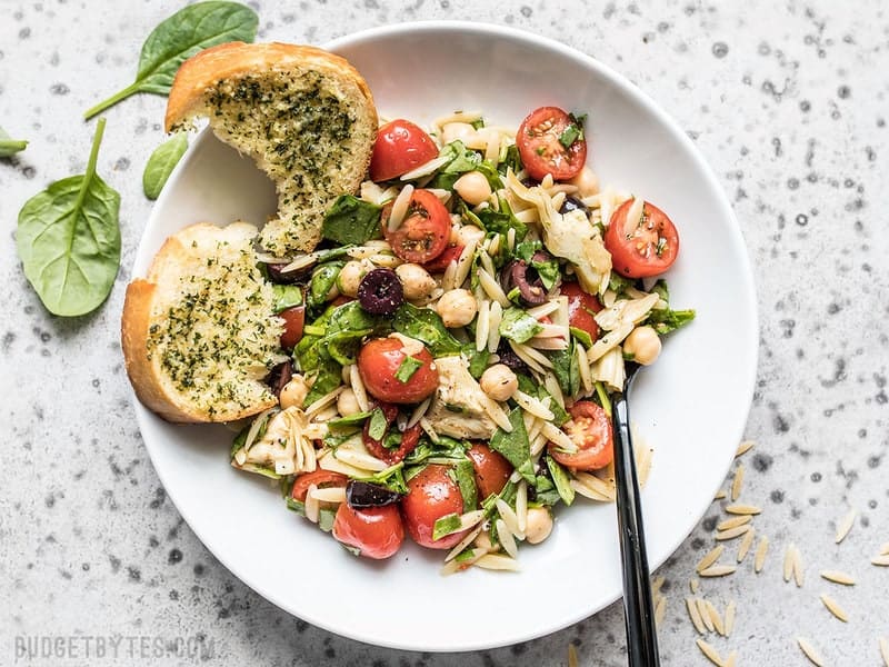 Bird's eye view of Italian Orzo Salad on a plate with a piece of garlic bread.