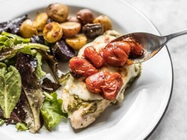 Close up of roasted tomatoes on top of Sheet Pan Pesto Chicken DInner