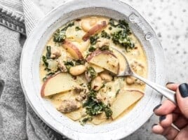 Overhead view of a bowl of Zuppa Toscana with a spoon dipping into the center.