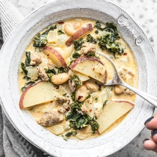 Overhead view of a bowl of Zuppa Toscana with a spoon dipping into the center.