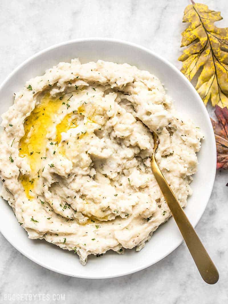 A big bowl of super fluffy Garlic Herb Mashed Potatoes with melted butter.