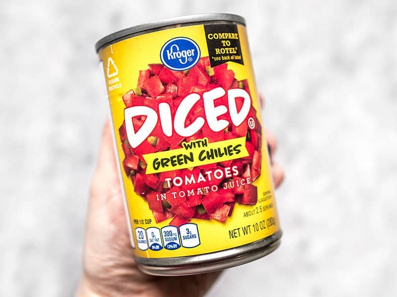 A can of diced tomatoes with green chiles being held in a hand