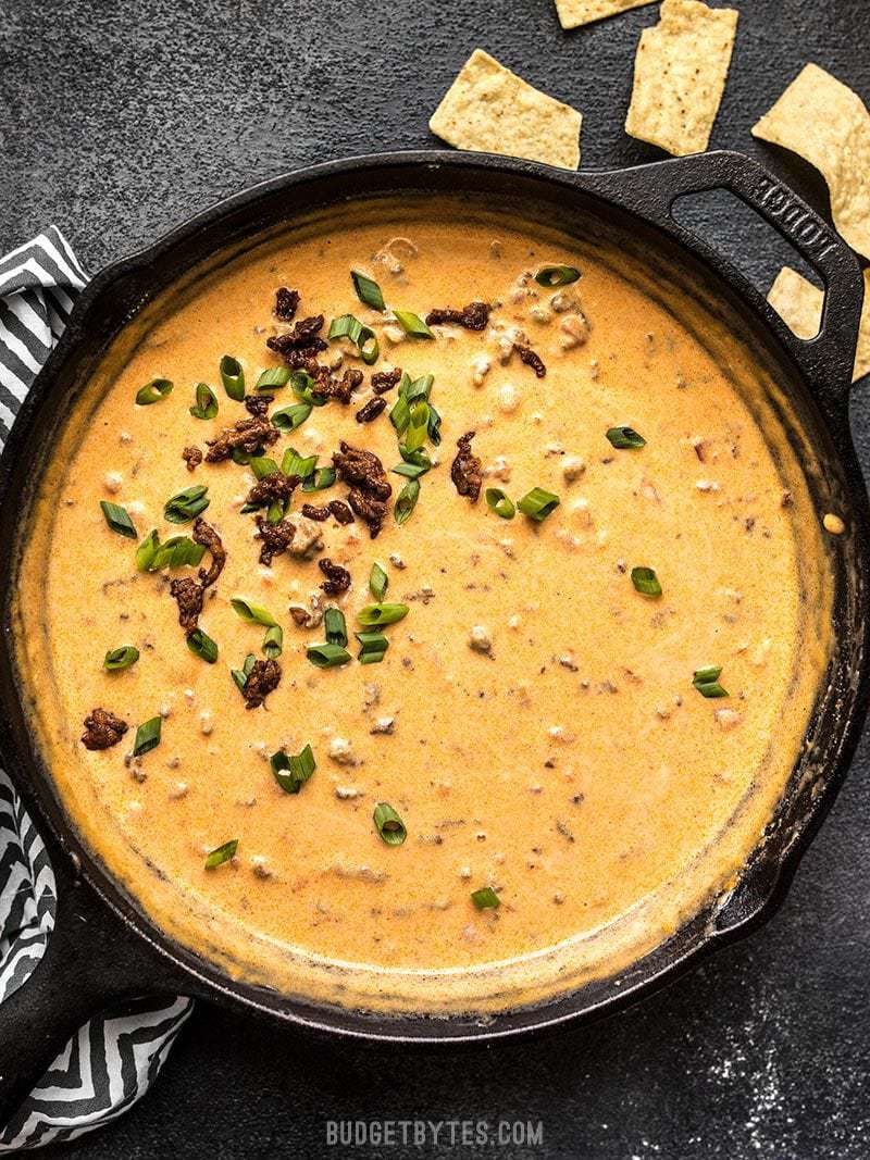 A skillet full of Spicy Chorizo Cheese Dip garnished with green onions.