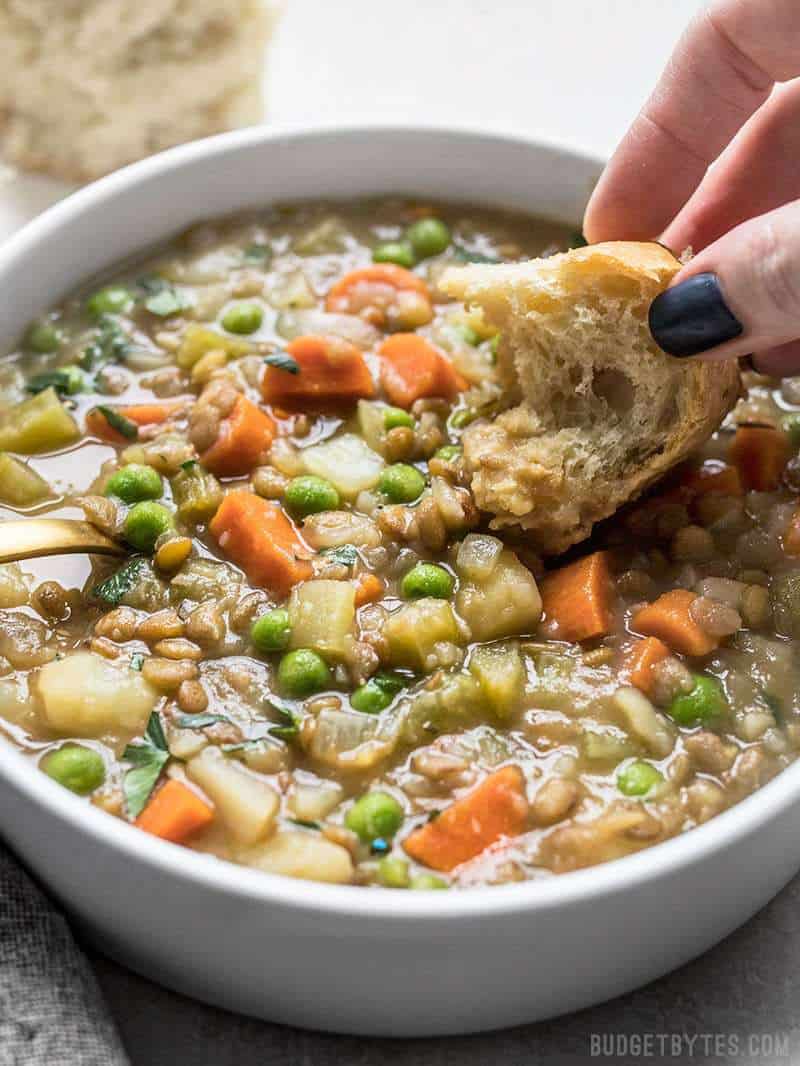Bread being dipped into a bowl of Vegan Winter Lentil Stew