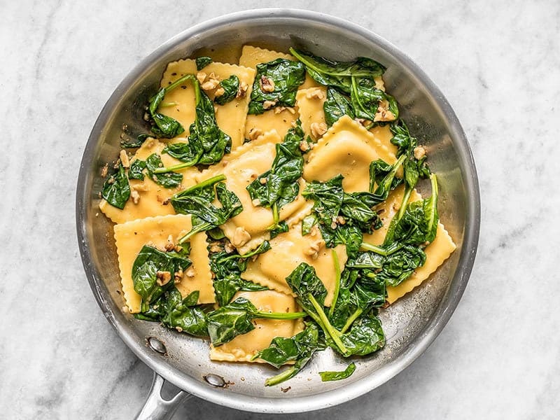 Wilted spinach and ravioli in the skillet with the brown butter sauce