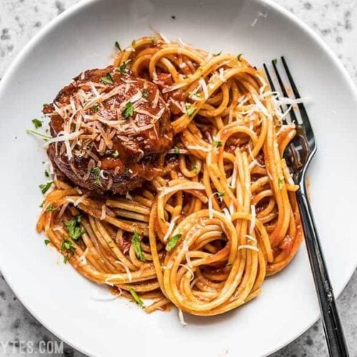 A plate with spaghetti, marinara, and a giant slow cooker meatball.