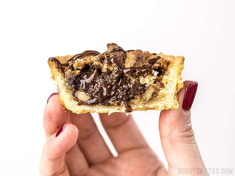 Close up of a Mini Dark Chocolate Pecan Pie cut in half.