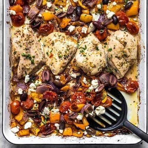 Sheet Pan Greek Chicken and Vegetables being scooped off the sheet pan with a spatula.