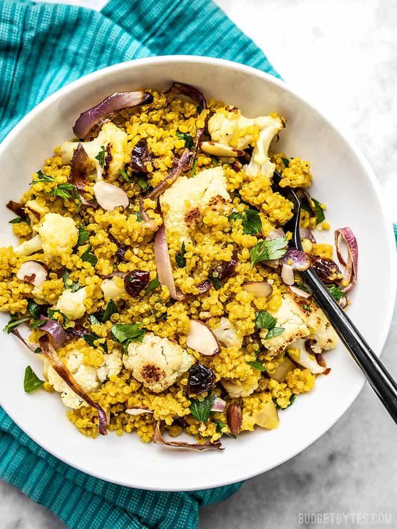 A bowl full of Roasted Cauliflower and Quinoa Salad on a teal napkin.