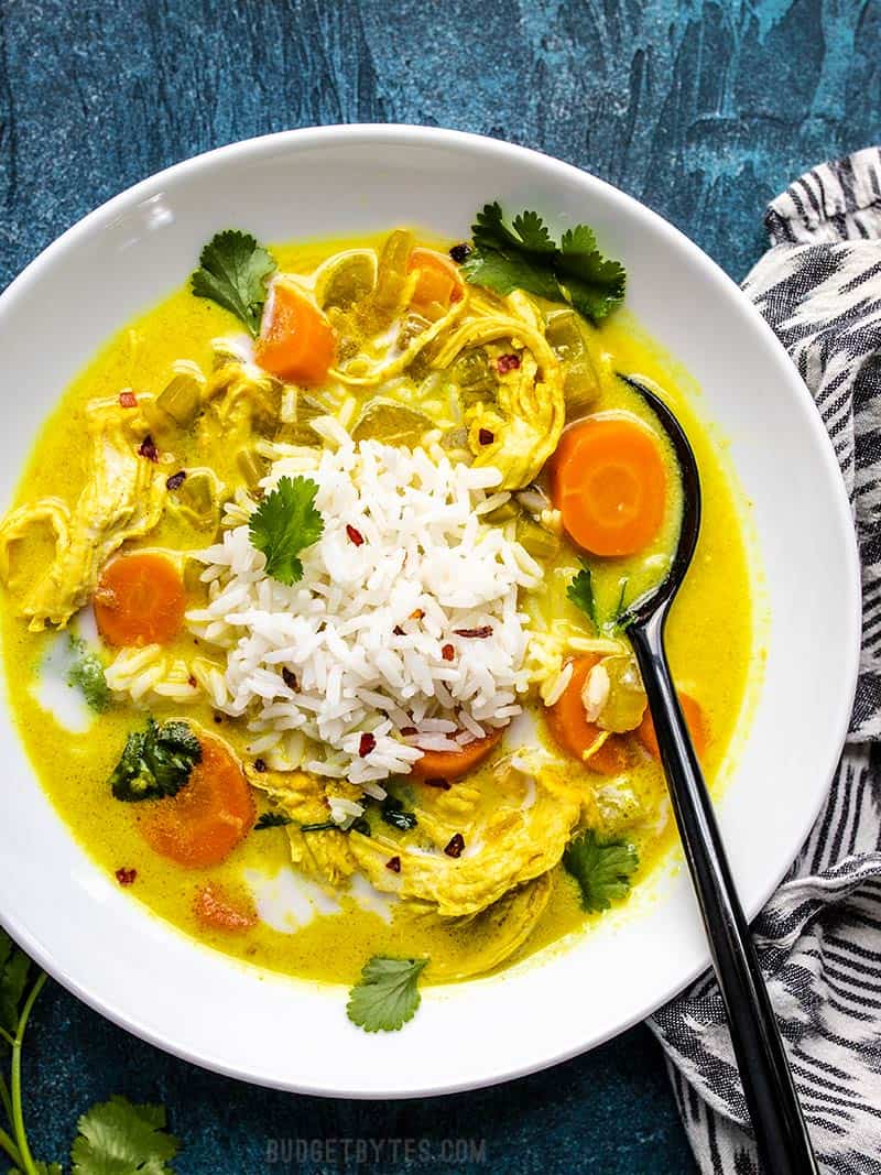 A big bowl of Coconut Turmeric Chicken Soup topped with rice and cilantro.