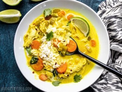 Coconut Turmeric Chicken Soup being eaten with rice and cilantro