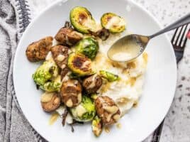 Creamy Dijon Dressing being Drizzled onto a Roasted Brussels Sprout Bowl