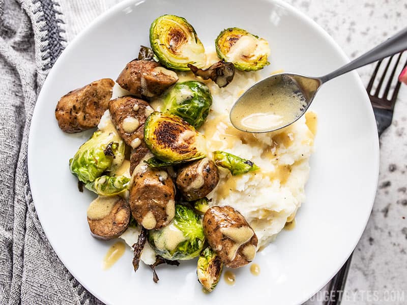 Creamy Dijon Dressing being Drizzled onto a Roasted Brussels Sprout Bowl