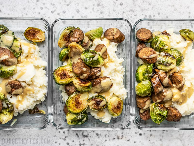 Three glass meal prep containers full of Roasted Brussels Sprout Bowls lined up.