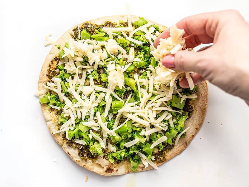 Add broccoli and shredded mozzarella to the pesto topped tortilla
