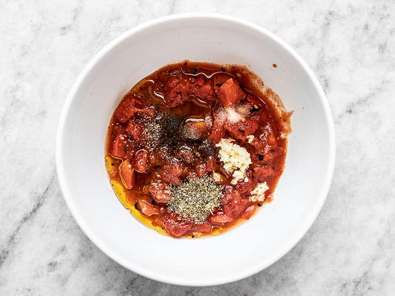 Fire roasted diced tomatoes, garlic, olive oil, oregano, salt, pepper, and lemon juice in a bowl