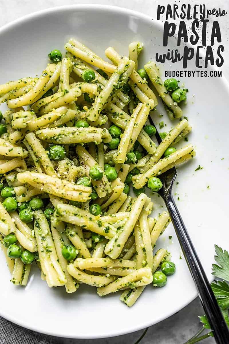 Close up of a bowl of Parsley Pesto Pasta with Peas, a black fork in the side of the bowl.