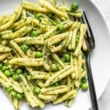 Parsley Pesto Pasta with Peas in a white bowl with a black fork in the side.