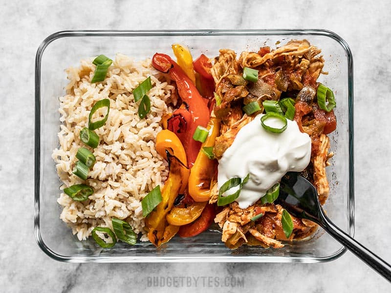 Salsa chicken meal prep container close up, topped with green onion and sour cream