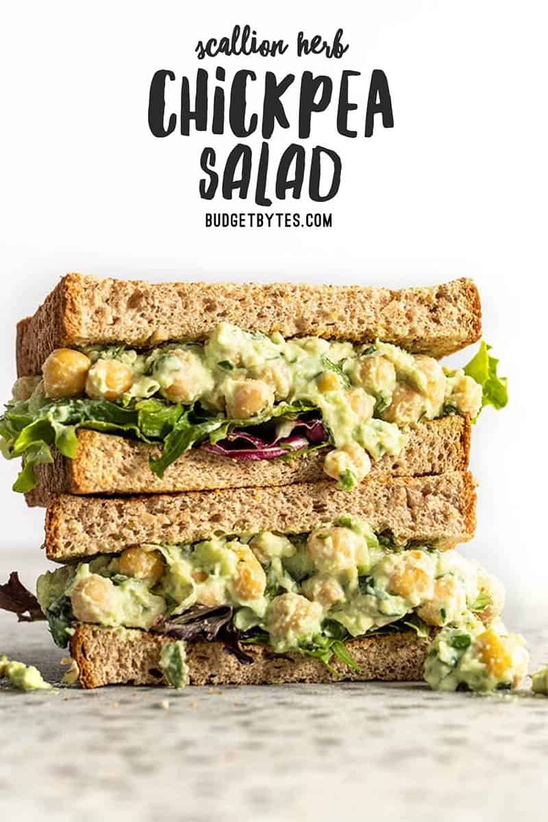 Two stacked halves of a Scallion Herb Chickpea Salad on wheat bread with spring mix