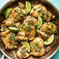 Close up of Easy Cilantro Lime Chicken in the skillet, garnished with cilantro and lime wedges.
