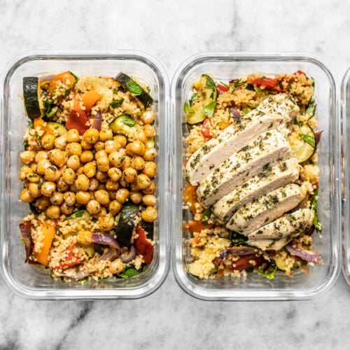 Four glass meal prep containers lined up with roasted vegetable couscous. Two with chicken and two with chickpeas