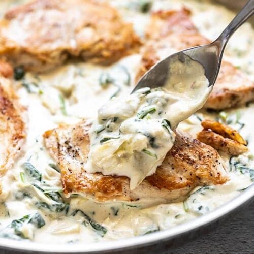 Creamy Spinach Artichoke Sauce being spooned over a piece of browned chicken