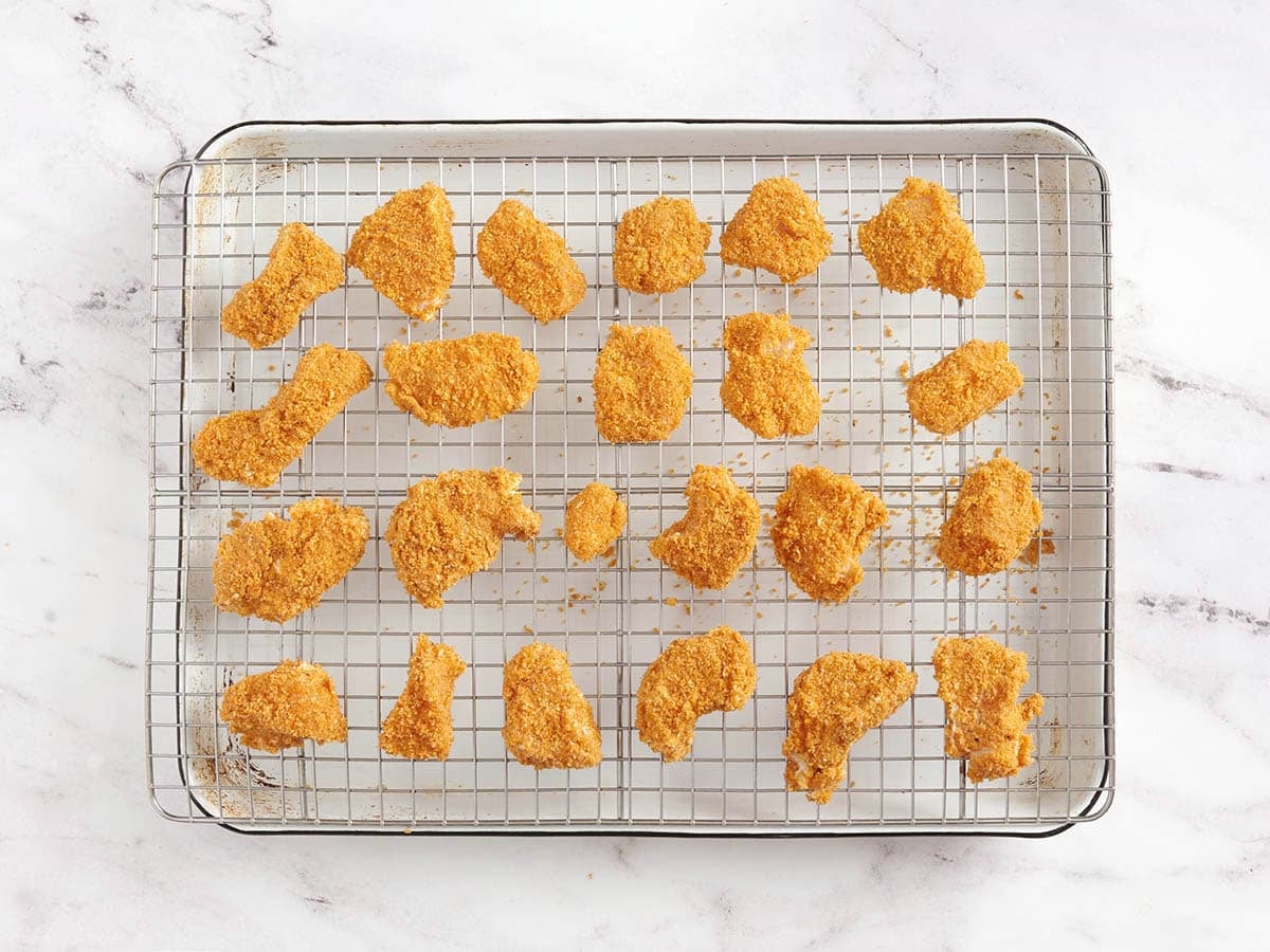 Coated chicken nuggets on a wire rack.