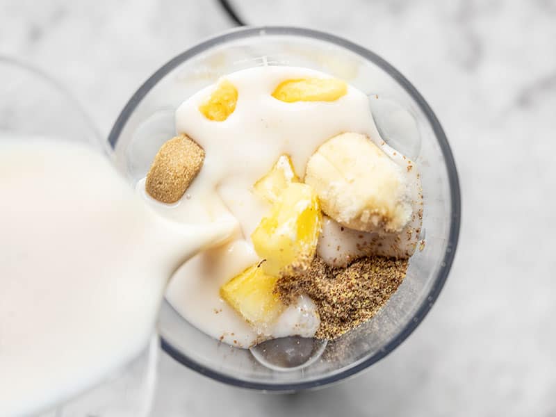 Almond milk being added to blender with other smoothie ingredients
