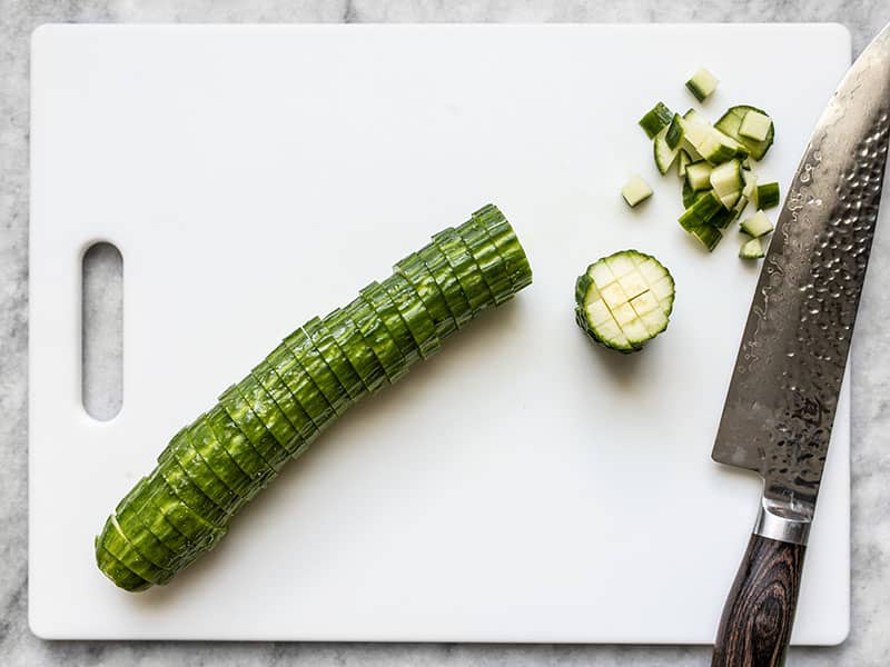 Cucumber being diced on a cutting board