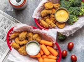 Two baskets with Homemade Baked Chicken Nuggets, vegetables, and two types of dip.