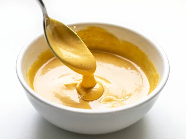 Honey Mustard Sauce dripping off a spoon into a bowl