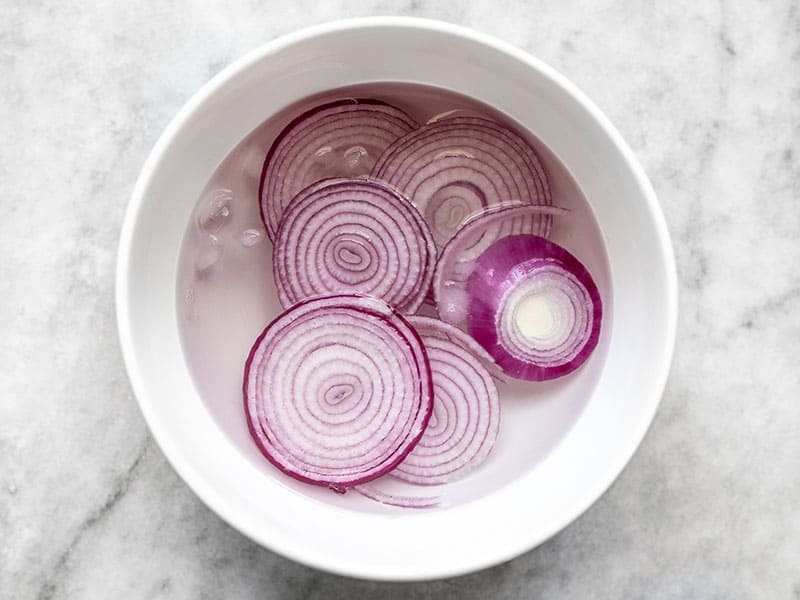 Sliced red onion soaking in ice water