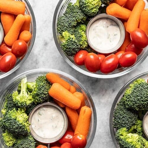 Four glass bowl veggie snack packs with ranch dressing, broccoli, and tomatoes.