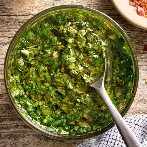 Overhead view of a bowl of chimichurri sauce with a spoon.