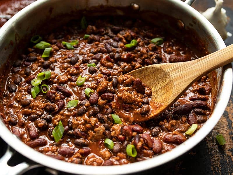 Close up of BBQ Beef and Beans in the skillet, topped with sliced green onion.