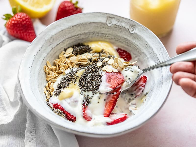 Front view of a spoon lifting a bite of the lemon berry yogurt breakfast bowl out of the bowl.